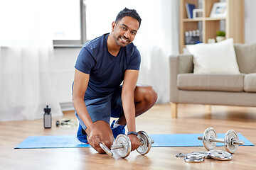 Image showing smiling indian man assembling dumbbells at home