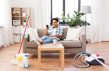 Image showing woman in headphones resting after home cleaning