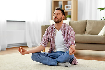 Image showing man meditating in lotus pose at home