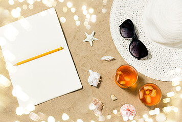 Image showing notebook, cocktails, hat and shades on beach sand