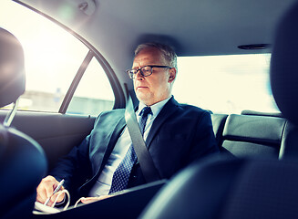 Image showing senior businessman with papers driving in car