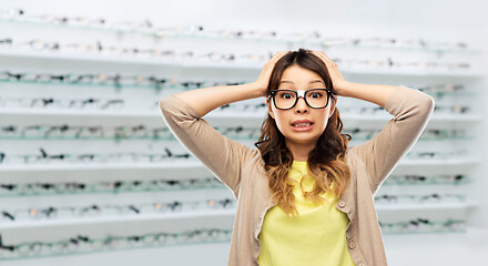 Image showing woman in glasses holding to head at optics store