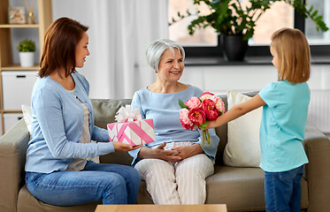 Image showing granddaughter giving flowers to grandmother