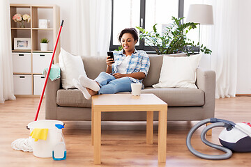 Image showing woman with smartphone resting after home cleaning