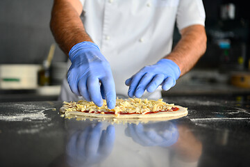 Image showing chef  with protective coronavirus face mask preparing pizza