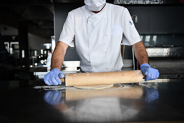 Image showing chef  with protective coronavirus face mask preparing pizza