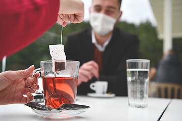 Image showing couple with protective medical mask  having coffee break in a re