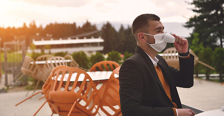 Image showing funny man in restaurant drinking coffee wearing face mask