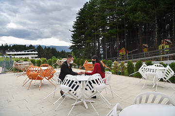 Image showing couple with protective medical mask  having coffee break in a re