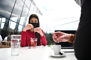 Image showing couple with protective medical mask  having coffee break in a re