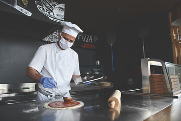 Image showing chef  with protective coronavirus face mask preparing pizza