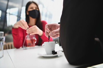 Image showing couple with protective medical mask  having coffee break in a re