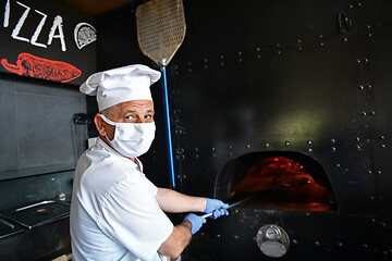 Image showing chef  with protective coronavirus face mask preparing pizza