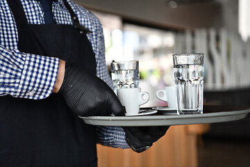 Image showing waiter in a medical protective mask serves  the coffee in restau