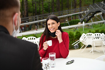 Image showing couple with protective medical mask  having coffee break in a re