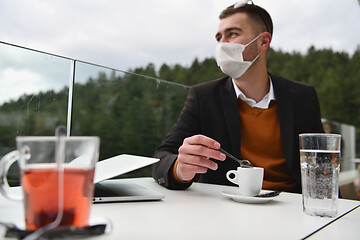 Image showing man in restaurant drinking coffee wearing face mask