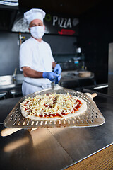 Image showing chef  with protective coronavirus face mask preparing pizza