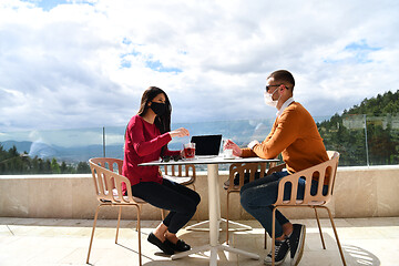 Image showing couple with protective medical mask  having coffee break in a re