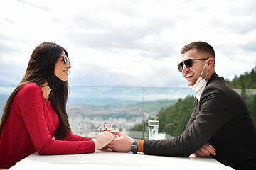 Image showing couple with protective medical mask  having coffee break in a re