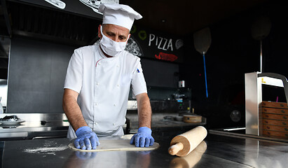 Image showing chef  with protective coronavirus face mask preparing pizza