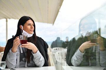 Image showing woman in restaurant drinking tea wearing face mask