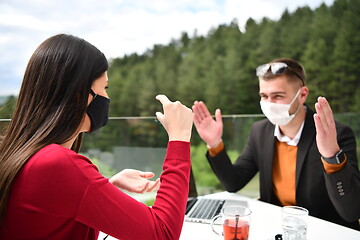 Image showing couple with protective medical mask  having coffee break in a re