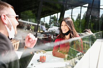 Image showing couple with protective medical mask  having coffee break in a re