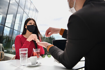 Image showing couple with protective medical mask  having coffee break in a re