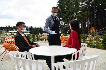 Image showing Waiter with protective medical mask and gloves serving guest