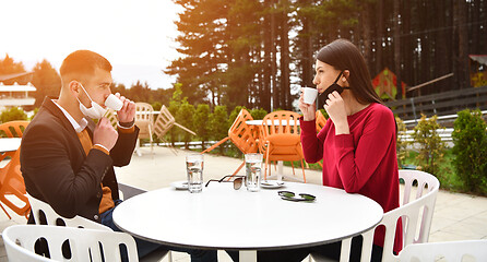 Image showing couple with protective medical mask  having coffee break in a re