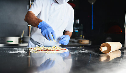 Image showing chef  with protective coronavirus face mask preparing pizza