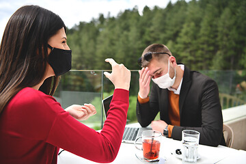 Image showing couple with protective medical mask  having coffee break in a re