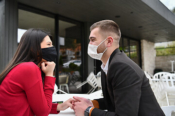 Image showing couple with protective medical mask  having coffee break in a re