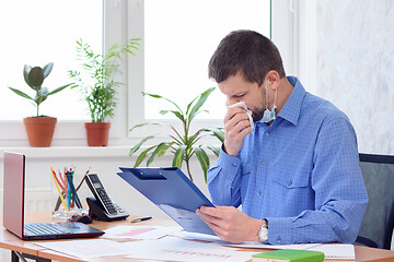 Image showing diseased workaholic in the office works with documents and swipes in a napkin