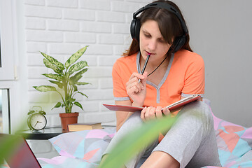 Image showing Girl in home clothes and decor teaches lessons and listens to a lecture online.