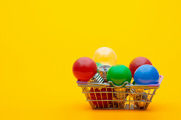 Image showing multi-colored light bulbs in a metal basket on a yellow background