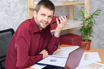 Image showing Man in the office listens to voicemail on mobile phone