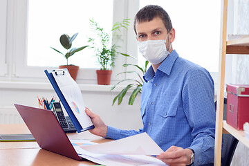 Image showing Office worker in medical mask examines data in documents with amazement