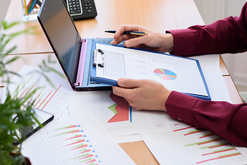 Image showing close-up of the office worker holding a tablet with documents and graphs