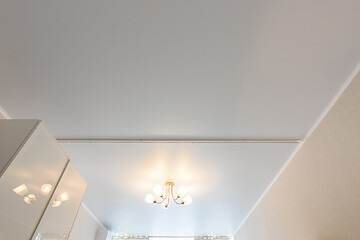 Image showing Classic white matte stretch ceiling with five lamp chandelier in the center