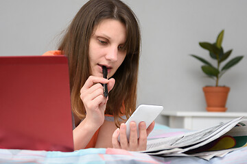 Image showing Girl thought looking at the screen of a mobile phone while looking for work