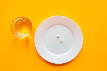 Image showing On the plate are two tablets, next is a glass of water