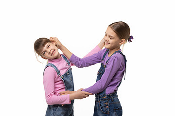 Image showing The eldest girl drags the younger one by the ear, isolated