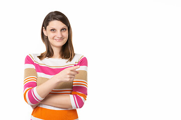 Image showing Girl with a charming smile points a finger to an empty place, white background