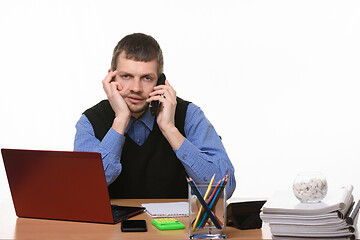 Image showing tired employee talking on the phone in an office setting