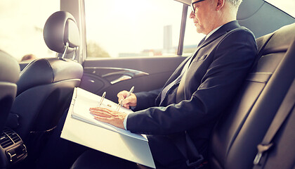 Image showing senior businessman with papers driving in car