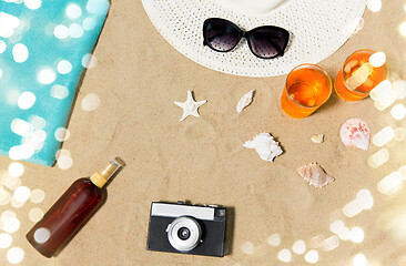 Image showing drinks, hat, camera and sunglasses on beach sand