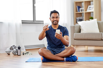 Image showing indian man with smartphone on exercise mat at home