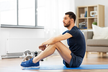 Image showing man resting on exercise mat at home