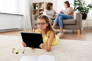 Image showing girl with tablet computer lying on floor at home